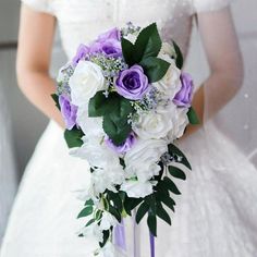 a bride holding a purple and white bouquet