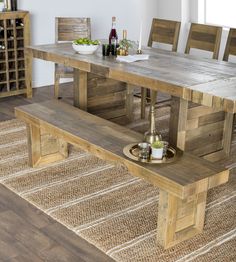 a wooden table and bench in a room with wood flooring, white walls and rugs