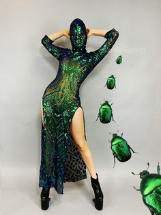 a woman in a green and black dress with her hands on her head, surrounded by bugs