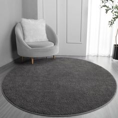 a round rug in the corner of a room with a chair and potted plant