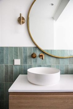 a bathroom sink with a round mirror above it