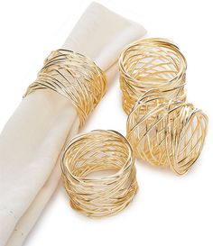 four gold napkin rings sitting on top of a white napkin next to an empty napkin