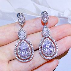 A delightfully unique pair of bridal earrings with an incredible sparkle! Adorned with flawlessly faceted cubic zirconia that capture the light in a dazzling array of sparkles, the earrings are rhodium plated for a bright finish which enhances the intricate detailing and conveys a modern take on old elegance. Overall length of the earring is 1.5" (approx. 4cm). Available in Silver, Rose Gold and Yellow Gold finishes. To make your choice select your preferred finish from the dropdown menu to add Exquisite Diamond White Crystal Earrings, Diamond White Cubic Zirconia Bridal Earrings For Party, Rose Gold Cubic Zirconia Diamond Earrings For Wedding, Glamorous Diamond White Cubic Zirconia Earrings, Glamorous Rose Gold Crystal Earrings With Cubic Zirconia, Dazzling Cubic Zirconia Chandelier Earrings For Anniversary, Rose Gold Bridal Earrings With Sparkling Cubic Zirconia, Glamorous Rose Gold Cubic Zirconia Crystal Earrings, Dazzling Cubic Zirconia Earrings For Party