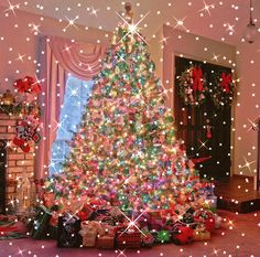 a christmas tree is lit up in the living room with presents on the floor and lights all around it