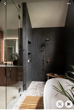 a bathroom with a walk in shower next to a bathtub and sink area that has a wooden bench on the side