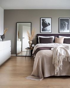 a large bed sitting in a bedroom next to two pictures on the wall above it