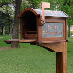 a wooden mailbox sitting on top of a lush green park