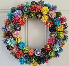 a wreath made out of fake flowers on the front door with a white door frame