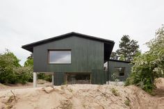 a green house sitting on top of a sandy hill