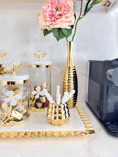 gold and white vases with flowers in them on a tray next to a microwave