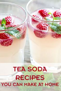 two glasses filled with ice and raspberries on top of a table next to mint leaves