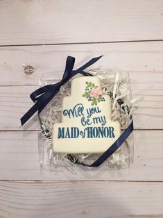 a decorated cookie in a clear box with blue ribbon on it that says, will you be my maid - of - honor?