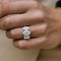 a person wearing a three stone ring on their finger