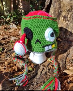 a crocheted green hat with eyes and mouth