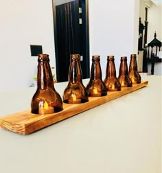 six brown glass bottles sitting on top of a wooden tray next to a candle holder