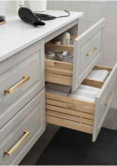 an open drawer in a white kitchen next to a counter