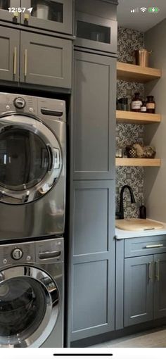 a washer and dryer in a small room with shelves on the wall behind them