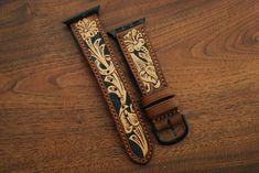 This is a 100% hand tooled watch strap with Sheridan style tooling, done on the highest quality natural veg tan in the US. Dyed golden brown with the background dyed black by hand with a fine brush. This style of tooling is a traditional western art typically done during saddle making. Lined with soft, tobacco colored veg tan pigskin. Add some traditional leatherwork to your modern Apple Watch. Available for all Apple watches in black, gold, rose gold, and matte silver. Straps are 22mm wide tapered down to 20mm. Point length is 120mm and buckle length is 80mm. If you would like custom sizing, please contact me, it should not be a problem. Please note that since the tooling is hand done, patterns may slightly vary from strap to strap. Luxury Hand Tooled Brown Bracelet, Apple Watch Accessories Bands, Apple Watch Leather Strap, Apple Watch Accessories, Golden Brown, Western Leather, New Bands, Pig Skin, Apple Watch Strap