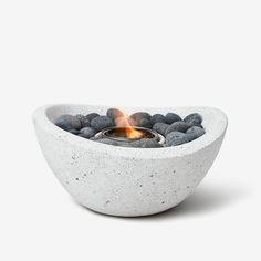 a white bowl filled with rocks and a lit candle in it's centerpiece