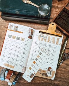 an open planner sitting on top of a wooden table next to a pair of glasses