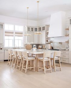 a large kitchen with white cabinets and wooden floors