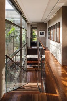 an empty hallway with wooden floors and glass railings