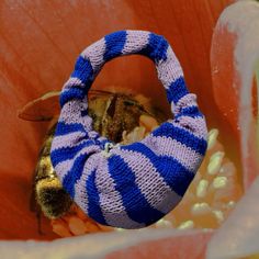 a blue and white knitted flower with a bee inside