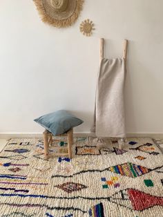 a room with a rug, chair and wall hangings on the wall next to it