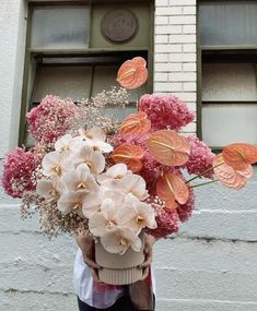 a person holding a bouquet of flowers in front of a building with windows on the side