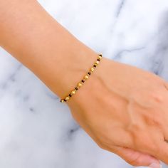 This dainty alternating 22k gold bracelet, weighing 4.3 grams, presents a polished yellow gold finish, elegantly complemented by black beads. The design, featuring a bracelet length of 7 inches, includes 0.6" adjustable links for a customized fit, secured with a hook lock. Ideal for those who value subtle elegance and refined detail, this piece harmoniously blends the luster of gold with the sophistication of black beads. It offers a versatile and stylish accessory, perfect for adding a touch of Black Beads Bracelet Gold, Black Bead Bracelet, 22k Gold Bracelet, Black Pearl Bracelet, Mangalsutra Bracelet, Mangalsutra Chain, Gold Bracelet Simple, Bridal Jewelry Necklace, Diamond Pendant Sets