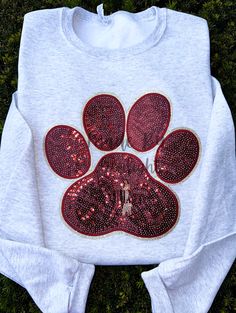 a white shirt with red sequins and a dog's paw on it