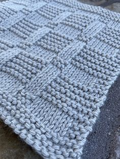 a knitted blanket sitting on top of a stone slab