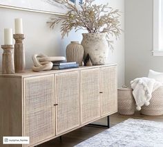 a living room with a rug, vases and other items on the sideboard