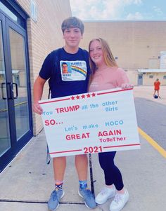 two people standing next to each other holding a sign