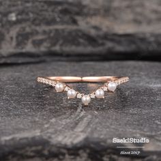 a gold ring with pearls and diamonds on top of a wooden surface in front of a stone wall