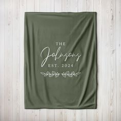 a green blanket with the words, the holidays est 2024 printed in white on it