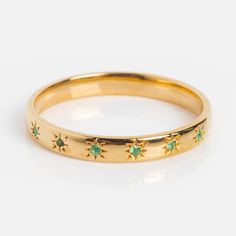 a gold ring with stars and green stones