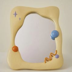 a yellow and blue mirror sitting on top of a white table next to a wall