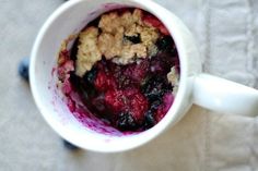 a close up of a bowl of food in a cup on a table with blueberries