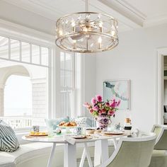 a dining room table and chairs with flowers in vases on the table next to it