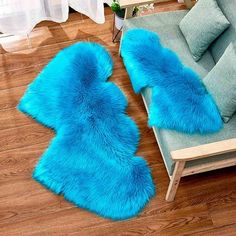 two blue fur rugs sitting on top of a wooden floor next to a couch