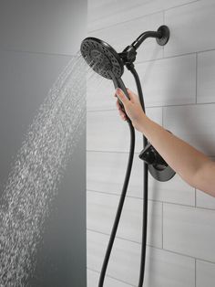 a person is holding the shower head and spraying it with water from its sprayer