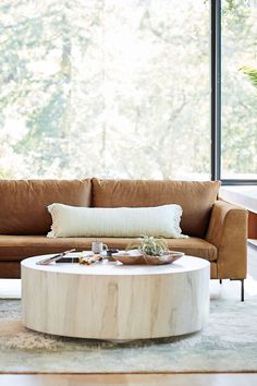 a living room with a couch, coffee table and large window overlooking the trees outside