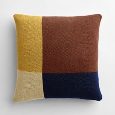 a brown, yellow and blue pillow sitting on top of a white wall