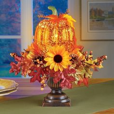 a vase filled with sunflowers and fall leaves