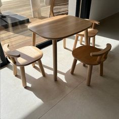 a wooden table and two chairs sitting in front of a sliding glass door on the floor