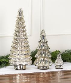 three silver christmas trees sitting on top of a table