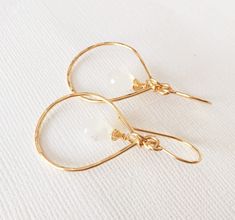 Moonstone tear drop briolettes dangle on a pair of petite tear drop hoops. Tear drop hoops is handmade with 14k gold filled wire and slightly hammered for textures and shines. Hoops are measure about 20x30mm in size. Moonstones are 10mm. Handmade 14k gold filled french ear wires. Earring's total length is about 1.5 inches including ear wires. Moonstone imparts a metal energy in Feng Shui. Metal energy supports healing, creativity, contraction and intelligence, all moonstone crystal benefits refl Crystal Benefits, Birthstone Earrings, Moonstone Crystal, Moonstone Earrings, Birthstone Earring, Bridesmaid Earrings, Moon Stone, Tear Drop, Bridesmaid Gift