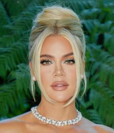 a woman with blonde hair wearing a choker necklace and pearls on her neck is looking at the camera