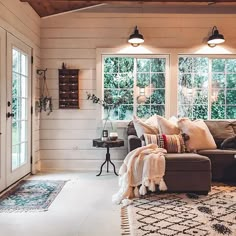 a living room with couches, rugs and two lamps on the ceiling in front of windows